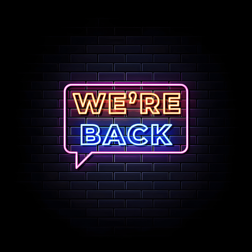 Neon sign "We're Back" against dark blue brick wall